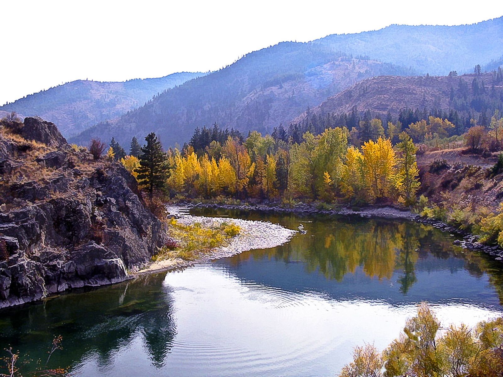 Calm river reflecting golden autumn trees and dark rock with hazy mountains behind