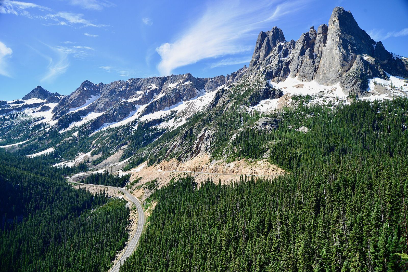 The North Cascades Highway winding over Washington Pass beneath the granite peak of Liberty Bell Mountain